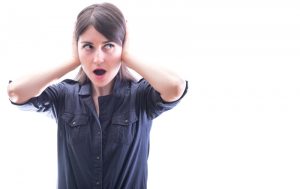 surprised-woman-covering-ears-and-standing-against-a-white-background