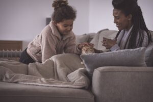 mother-and-daugher-on-couch-with-cat-staying-warm