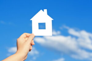 cardboard house in the hand against the blue sky